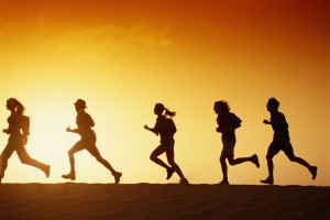 People running in desert at dusk, side view